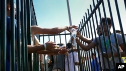 People reached out to grab water bottles as hundreds of migrants sought shelter outside an overcrowded asylum seekers center in Ter Apel, northern Netherlands, Aug. 25, 2022.