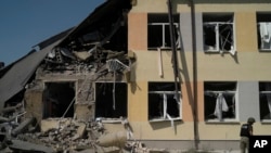 A Ukrainian serviceman stands in front of a heavily damaged school after a Russian attack in Druzhkivka, Donetsk region, eastern Ukraine, Aug. 30, 2022. 