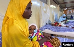 A woman carries a malnourished child at a treatment center in Damaturu, Yobe, Nigeria, Aug. 24, 2022.