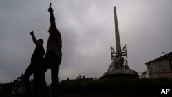 A statue honoring those who fought for Ukraine's freedom stands in Mostyska, western Ukraine, as organizers set up for an event marking the country's Independence Day, Aug. 24, 2022.