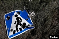 FILE - A road sign damaged by cluster munition is seen following a military strike, amid Russia's attack on Ukraine, on the outskirts of Kharkiv, Ukraine, June 10, 2022.