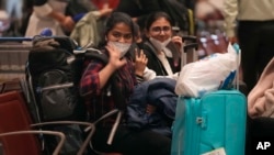 Indian students wave as a batch of 250 Indian nationals stranded in Ukraine arrived from Bucharest at Chhatrapati Shivaji Maharaj International Airport in Mumbai, India, Saturday, Feb. 26, 2022. (AP Photo/Rajanish Kakade)