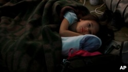 A child from Ukraine rests in a tent, part of a humanitarian center for refugees at the Moldovan-Ukrainian border, in Palalanca, Moldova, Feb. 25, 2022. Thousands of Ukrainians are fleeing from war by crossing their borders to the west in search of safety.