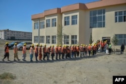 FILE - Afghan men stand in a queue for a program offered by Afghanistan's Taliban government to tackle hunger, offering thousands of people wheat in exchange for labor, in Dasht-e-Padula of southern Kabul, Oct. 24, 2021.