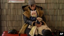 A family sits in the Kyiv subway, using it as a bomb shelter in Kyiv, Ukraine, Feb. 25, 2022.