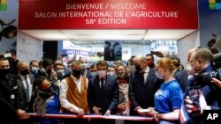 French President Emmanuel Macron cuts the ribbon as he inaugurates the International Agriculture Fair, in Paris, Feb. 26, 2022.