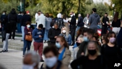 People stand in a queue as they wait to for rapid COVID 19 tests by the National Health Organization (EODY) in Athens, Greece, Nov. 5, 2020 where Prime Minister Kyriakos Mitsotakis has announced a nationwide three-week lockdown.