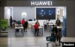 FILE - Customers and employees are seen at a Huawei store at Sandton City mall in Sandton, South Africa, Feb. 16, 2022.