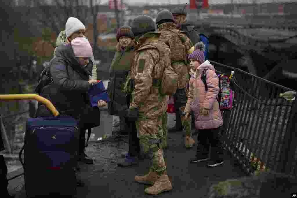 Ukrainian soldiers check people's identity cards as they flee their neighborhoods, on the outskirts of Kyiv, March 2. 2022.