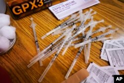 FILE - Prepared Pfizer COVID-19 vaccine syringes wait for patients at a middle school in Wheeling, Ill., June 11, 2021.
