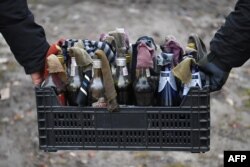 Relawan memegang keranjang dengan bom molotov buatan tangan selama kursus sipil bela diri di pinggiran Lviv, Ukraina barat. (Foto: AFP)