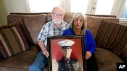 FILE - Joey and Paula Reed pose for a photo with a portrait of their son Marine veteran and Russian prisoner Trevor Reed at their home in Fort Worth, Texas, Feb. 15, 2022.