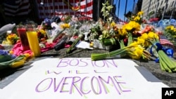 FILE - Flowers and signs adorn a barrier, two days after two explosions killed three and injured hundreds, at Boylston Street near the finish line of the Boston Marathon at a makeshift memorial for victims and survivors of the bombing, April 17, 2013.