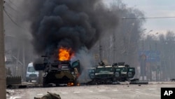 A Russian armored personnel carrier burns amid damaged and abandoned light utility vehicles after fighting in Kharkiv, Ukraine, Feb. 27, 2022. 