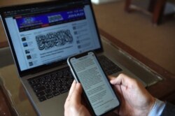 FILE - An Afghan reporter looks at messages sent by Taliban spokesman Zabihullah Mujahid in the newsroom at Maiwand TV station in Kabul, Feb. 6, 2019.