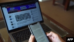 FILE - An Afghan reporter looks at messages sent by Taliban spokesman Zabihullah Mujahid in the newsroom at Maiwand TV station in Kabul, Feb. 6, 2019.