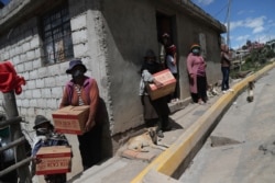 Residents wearing protective face masks hold food boxes distributed by the government during a lockdown to contain the spread of COVID-19, on the outskirts of Quito, Ecuador, May 27, 2020.