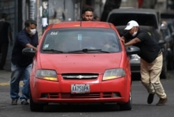 Men push a car that ran out of gas to a state-run oil company gas station, in Caracas, Venezuela, May 25, 2020.