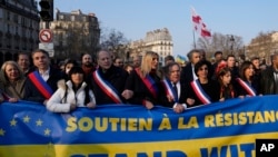 Wali Kota Paris dan kandidat presiden Anne Hidalgo (kanan) berpawai bersama sejumlah politisi sambil membawa spanduk bertuliskan “Berdiri Bersama Ukraina” dalam demo memprotes invasi Rusia ke Ukraina, di Paris, Prancis, Sabtu, 5 Maret 2022. (Foto: Francois Mori/AP)
