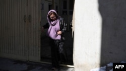FILE - Roya, an embroidery teacher who lost her job after the Taliban took power, walks through the entrance gate of her residence in Kabul, Jan. 24, 2022.