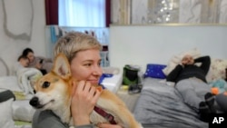 Olga Okhrimenko, 34 years-old, who fled the Russian invasion from Kharkiv on March 1, holds her dog Knolly as they sit inside a ballroom converted into a makeshift refugee shelter, in Suceava, Romania, Friday, March 4, 2022.