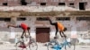Somali boys perform tricks on their bicycles near a ruined building in Hamarweyne district of Mogadishu, Jan. 25, 2021. With poor roads and equipment, Somalia's cycling federation faces an uphill battle to prepare for upcoming international competition.