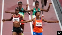 Sifan Hassan, of the Netherlands, foreground right, crosses the finish line ahead of Agnes Tirop, of Kenya, left, to win a heat in the women's 5,000-meter run at the 2020 Summer Olympics, July 30, 2021, in Tokyo. 