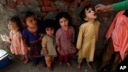 FILE - A health worker administers a polio vaccine to a child in Lahore, Pakistan, Feb. 28, 2022, as other children line up.