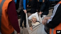Klavidia, 91, is carried on an improvised stretcher as she flees the war by boarding a train in Pokrovsk, Ukraine, on April 25, 2022.