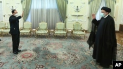 In this photo released by the Office of the Iranian Presidency, President Ebrahim Raisi, right, and China's minister of national defense Gen. Wei Fenghe greet each other at the start of their meeting in Tehran, Iran, April 27, 2022.