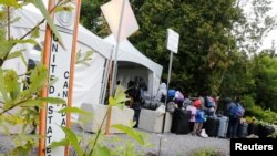 A line of asylum seekers wait to enter into Canada from Roxham Road in Champlain, New York, August 7, 2017.
