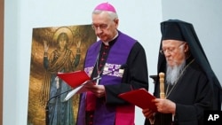 The spiritual leader of the world's Orthodox Christians, Ecumenical Patriarch Bartholomew I, right, and Archbishop Stanisław Gądecki, the head of the Polish Bishops' Conference, stand together as they meet with Ukrainian refugees in Warsaw, Poland, on Mar