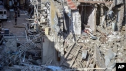 People look at the destroyed houses a day after shelling by Armenian's artillery during fighting over the separatist region of Nagorno-Karabakh, in Ganja, Azerbaijan, Oct. 12, 2020.