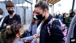 A woman from Ukraine stands with her children before crossing into the United States, March 10, 2022, in Tijuana, Mexico.