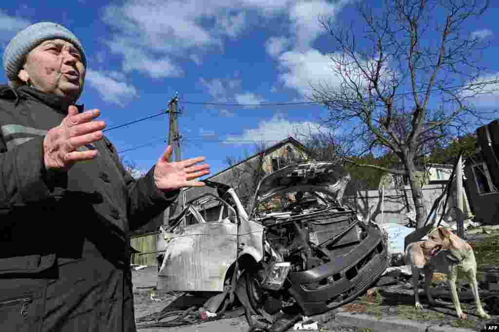 A local retiree Nataliya Mykolaivna, 64, talks to an AFP journalist next to a minibus destroyed by Russian shelling at a short distance from the frontline in Horenka, northern Kyiv, March 10, 2022. The minibus brought supplies and gifts to frontline soldiers, volunteers and hard-pressed residents.