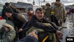 A man waits for an ambulance to arrive to evacuate his father to a safer location, in Ukraine, March 8, 2022. (Yan Boechat/VOA)