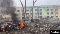 FILEL - A view shows cars and a building of a hospital destroyed by an aviation strike amid Russia's invasion of Ukraine, in Mariupol, Ukraine, in this handout picture released March 9, 2022 by the Press service of the National Police of Ukraine.