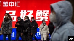 Commuters wearing face masks walk out of a subway station in the central business district in Beijing, Jan. 12, 2023. 