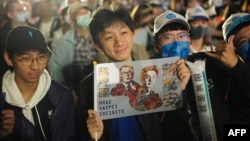 A supporter of the main opposition Kuomintang (KMT) and candidate Chiang Wan-an (not pictured) displays a placard during a mayoral election campaign rally in Taipei on Nov. 26, 2022.