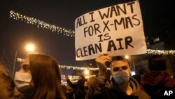 FILE - A high school student holds up a banner protesting dangerous levels of air pollution, in front of the government building in Skopje, North Macedonia, Dec. 20, 2019.