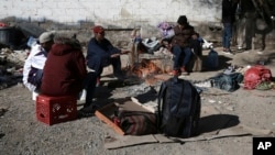 FILE - Migrants sit around a fire at a shelter on the U.S.-Mexico border in Ciudad Juarez, Mexico, Dec. 19, 2022.