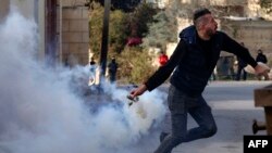 Seorang demonstran Palestina melempar tabung gas air mata yang ditembakkan pasukan Israel menyusul protes terhadap perampasan tanah Palestina oleh Israel di Tepi Barat, di Desa Kfar Qaddum, dekat pemukiman Yahudi Kedumim pada 6 Januari, 2023. (Foto: AFP)