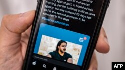 A person in the Cypriot capital Nicosia checks a mobile phone on December 12, 2022, displaying a Tweet about the execution announced by Iranian authorities of Majidreza Rahnavard, the second capital punishment linked to nearly three months of protests.