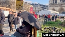 A homeless man sits outside Notre Dame cathedral in Paris. Life has gotten harder for Europeans since the war in Ukraine.
