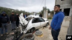 Palestinians look at a damaged car following an Israeli raid in the West Bank village of Jaba, Jan. 14, 2023.