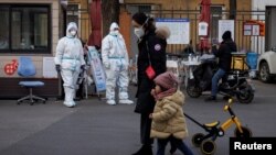 身穿防护服的大白站在北京一居民小区的大门处执勤。（2022年12月7日）