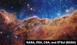 This landscape of “mountains” and “valleys” speckled with glittering stars is actually the edge of a nearby, young, star-forming region called NGC 3324 in the Carina Nebula. Courtesy of NASA, ESA, CSA, and STScI