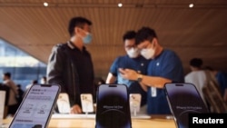 A customer talks to sales assistants in an Apple store as Apple new iPhone 14 models go on sale in Beijing, September 16, 2022. (REUTERS/Thomas Peter)