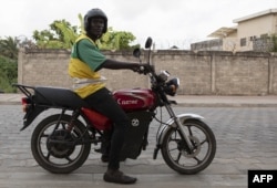 Un chauffeur de taxi moto sur sa moto électrique pose pour une photo dans les rues de Cotonou, le 21 octobre 2022.