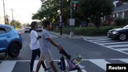 Una pareja colombiana se dirige a una parada de autobús para llevarlos de regreso al hotel en el que se hospedan con su hija Evangeline, de 1 año, luego de visitar el Mary's Center en Washington, EEUU, el 23 de agosto de 2022.